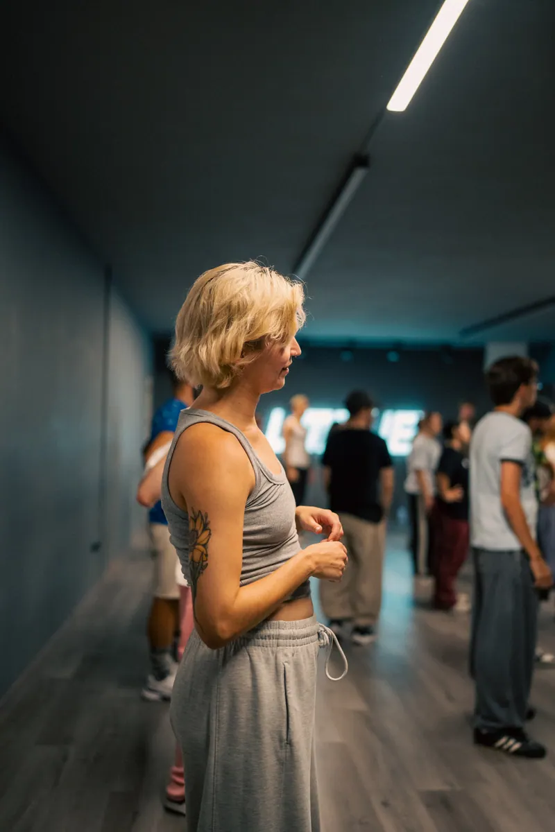 An UMOVE dancer training with a busy studio class behind her